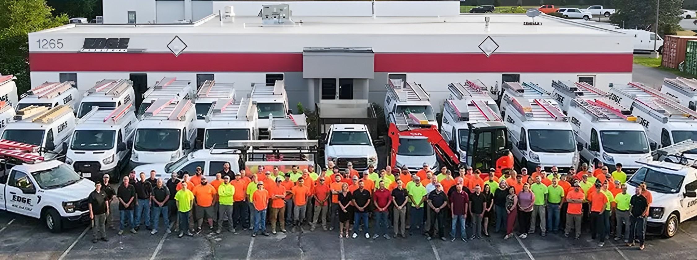 The Edge Electric team in hi-vis shirts in front of their fleet of service vans