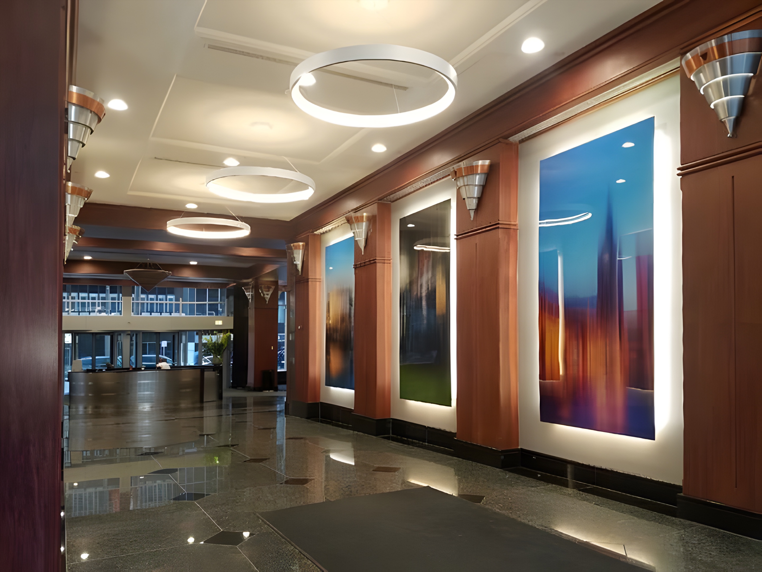 A lobby with ring pendant lights and backlit artwork panels
