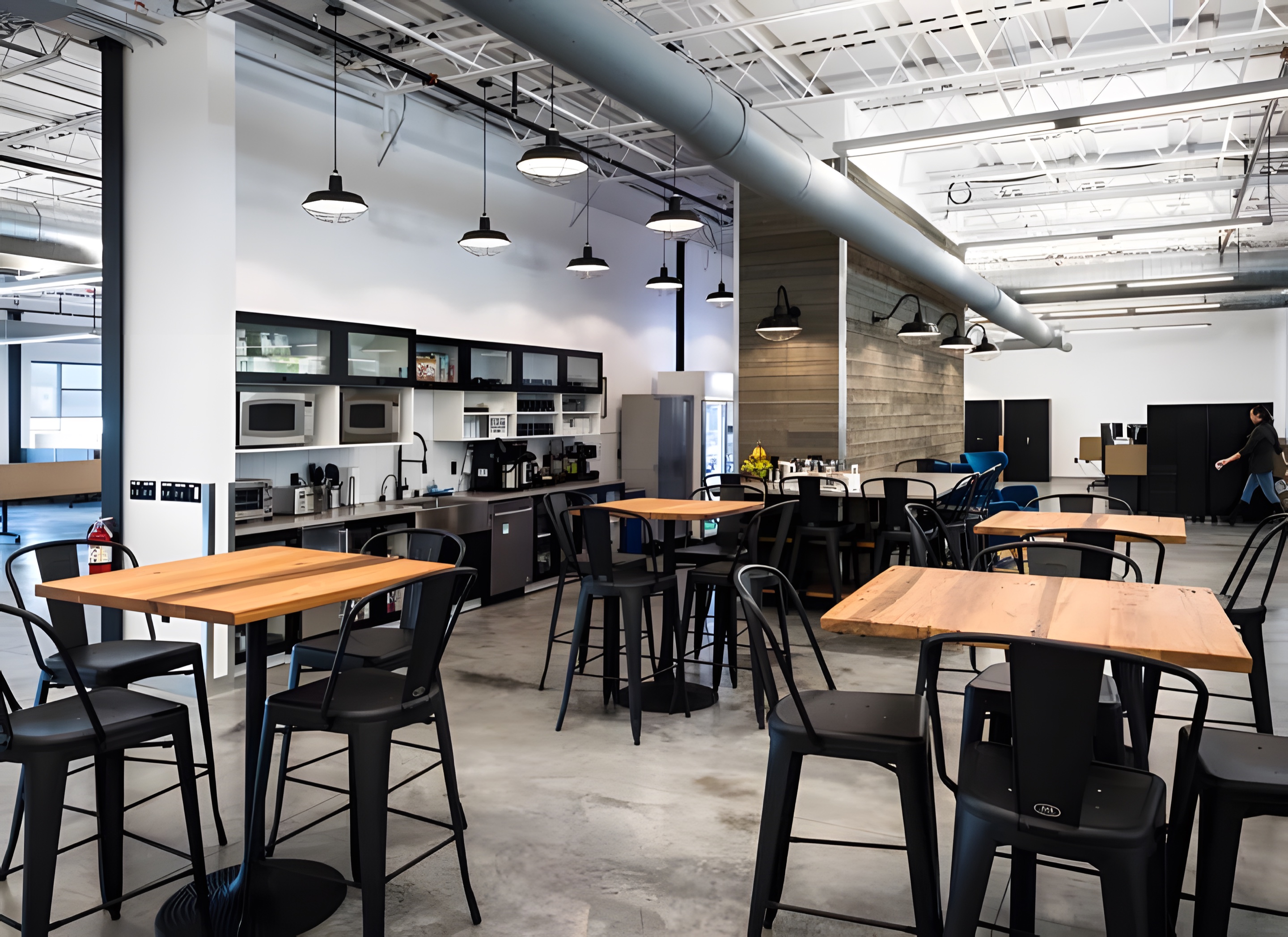 A break room with pendant lights over high-top tables